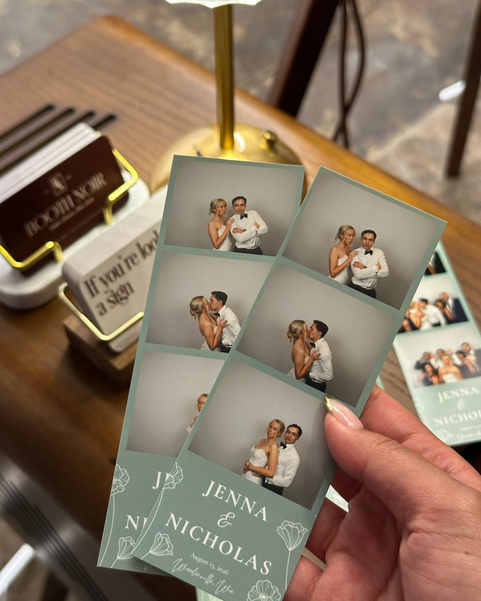 A guest holding two printed 2 by 6 strips of the couple, their names and the date at the foot of each