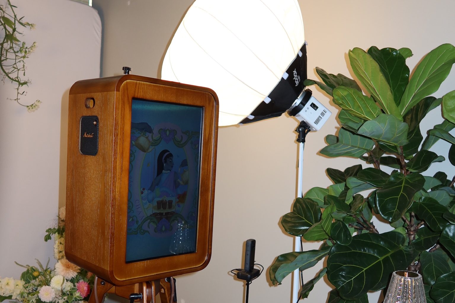 The booth lit by a softbox, with flowers and a fig tree on either side, at the brand's launch event