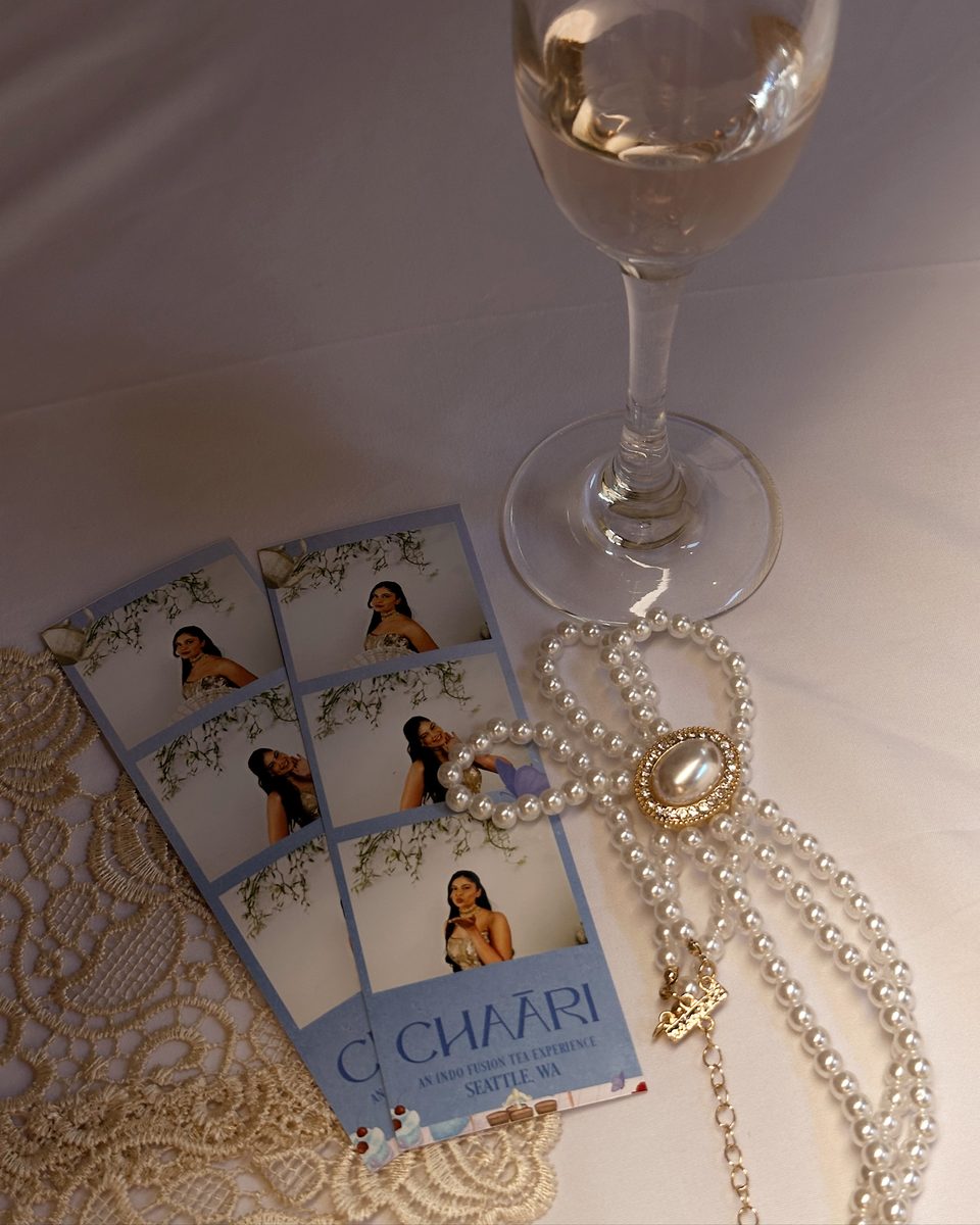 Printed strips from a brand event on lace beside a string of pearls and a glass