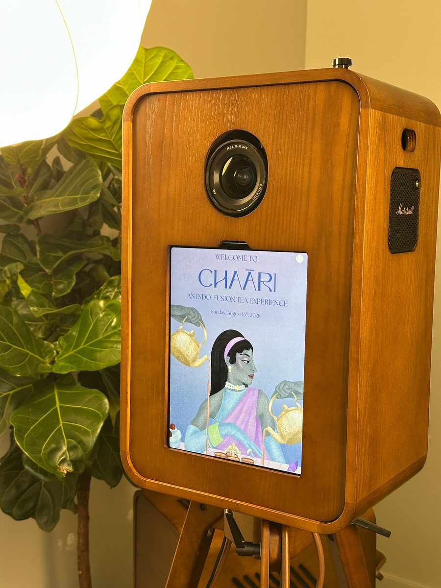The booth's front screen running a client's illustrated welcome design, beside a fig tree