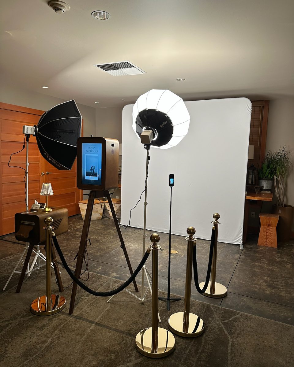 The booth, its lights, and the white backdrop set behind brass stanchions and a velvet rope, before guests arrive