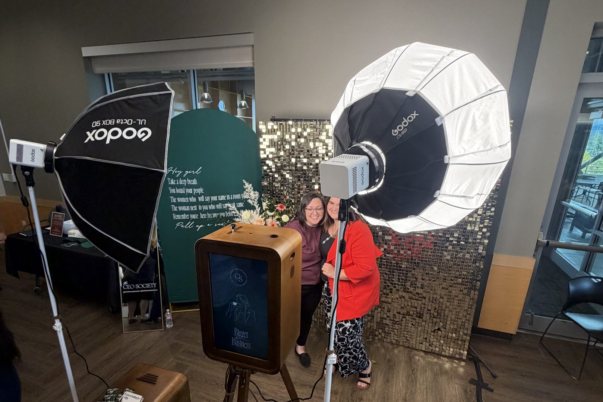 Two guests posing at the booth between its lights in front of a sequin wall