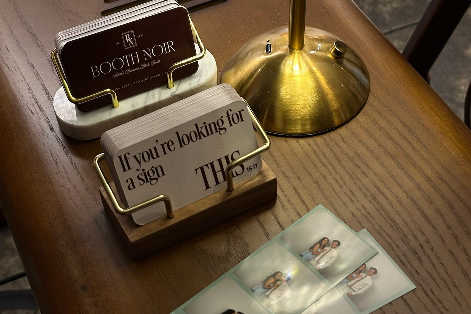 A printed strip on the booth's side table beside a lamp and the Booth Noir cards